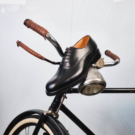 Schwarzer Schuh auf dem Lenker eines Fahrrads mit Holzgriffen.