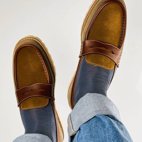 Braune Mokassins mit blauen Socken und Jeans, von oben fotografiert.